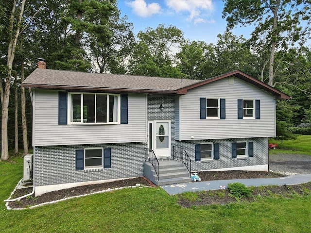 52 Bull Pine Rd, East Stroudsburg, PA 18301 - split foyer home featuring brick siding, a front lawn, a chimney, and view of wooded area