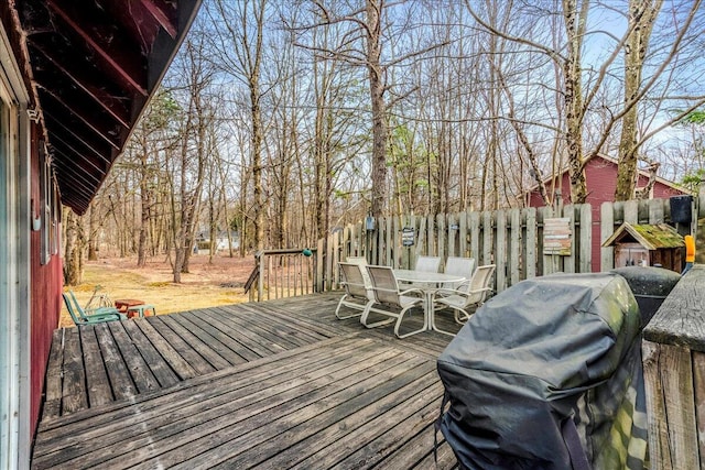 wooden terrace with fence, outdoor dining area, and area for grilling