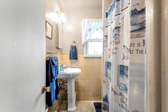 bathroom with wainscoting, a shower with curtain, tile patterned flooring, and tile walls