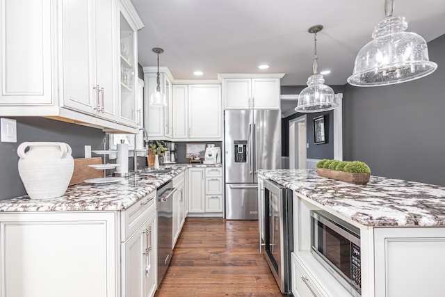 kitchen with hanging light fixtures, white cabinets, dark wood-style flooring, and stainless steel appliances