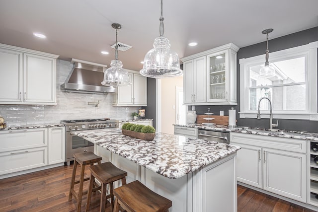 kitchen featuring visible vents, appliances with stainless steel finishes, white cabinetry, and wall chimney exhaust hood