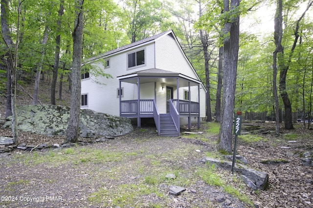 view of front of home featuring covered porch, roof with shingles, and stairs