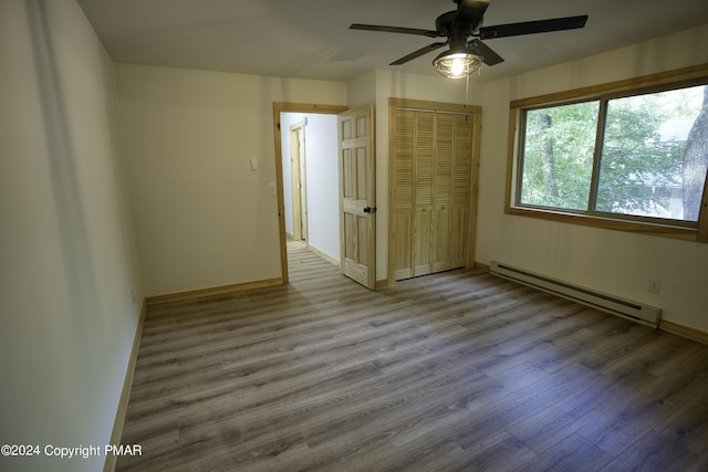 spare room featuring baseboards, baseboard heating, and wood finished floors