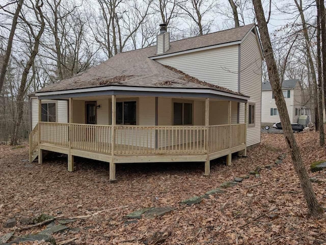 back of property with roof with shingles and a chimney