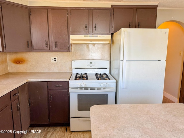 kitchen with light countertops, white appliances, backsplash, and under cabinet range hood