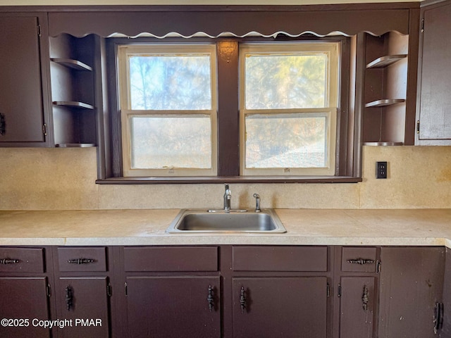 kitchen featuring tasteful backsplash, light countertops, a sink, and open shelves