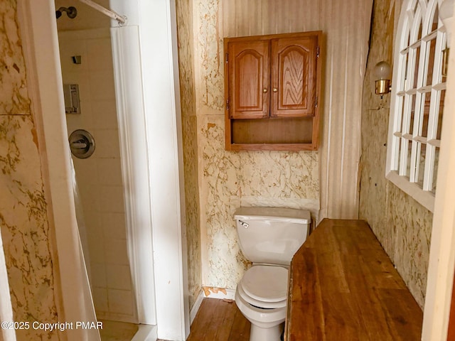 bathroom featuring a shower with shower curtain, wood finished floors, toilet, and wallpapered walls