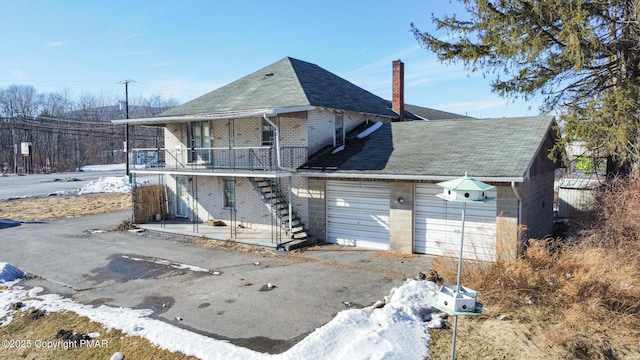 view of front of property featuring aphalt driveway, brick siding, a garage, and stairs