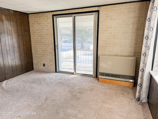 carpeted spare room featuring brick wall