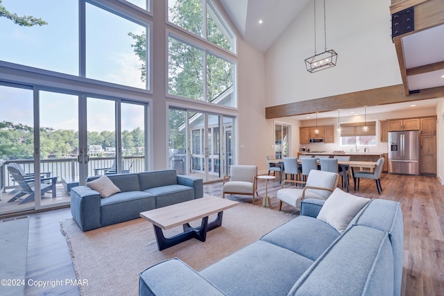 living room with light wood-style floors, high vaulted ceiling, and plenty of natural light