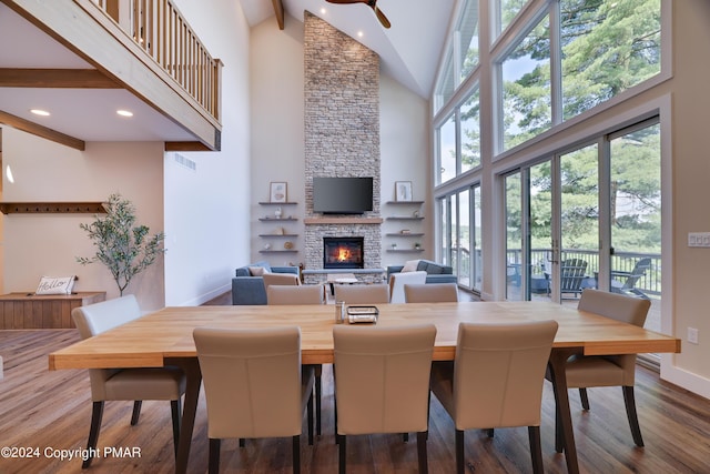 dining room featuring a stone fireplace, high vaulted ceiling, baseboards, recessed lighting, and dark wood-type flooring