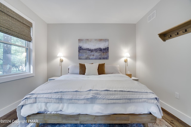 bedroom featuring baseboards, visible vents, and wood finished floors