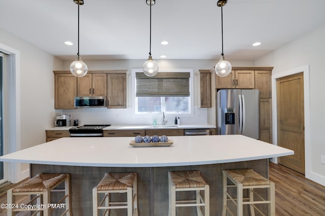 kitchen featuring a breakfast bar area, backsplash, hanging light fixtures, a sink, and stainless steel appliances