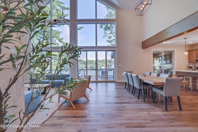 dining space with a water view, wood finished floors, and a towering ceiling