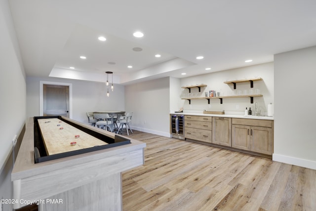 playroom with beverage cooler, light wood-style flooring, recessed lighting, wet bar, and a tray ceiling