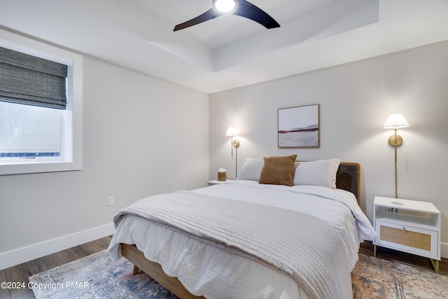 bedroom featuring baseboards, a ceiling fan, a raised ceiling, and wood finished floors
