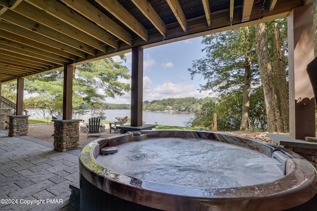 view of patio / terrace featuring a hot tub and a water view