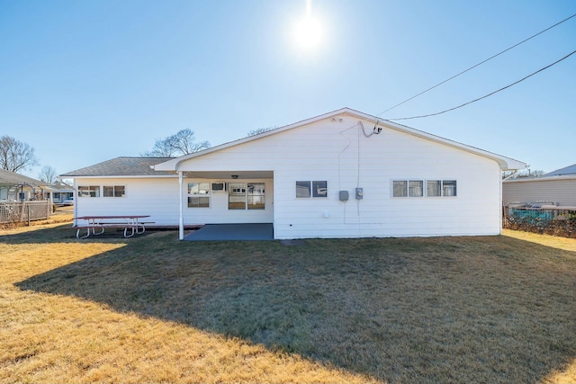 rear view of property featuring a patio, a lawn, and fence