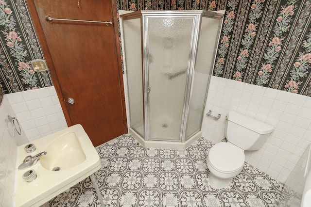 bathroom featuring tile patterned floors, a stall shower, tile walls, wainscoting, and wallpapered walls