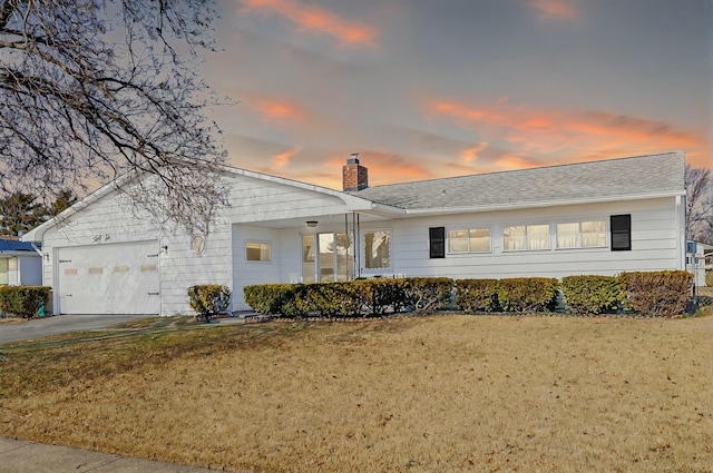 view of front of home with a front yard, an attached garage, driveway, and a chimney