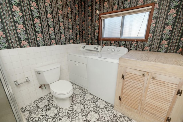 bathroom with a wainscoted wall, wallpapered walls, tile patterned floors, toilet, and washing machine and dryer