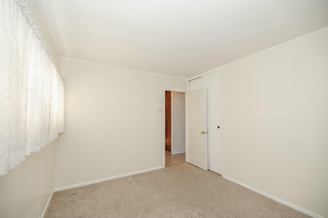 empty room featuring light carpet and baseboards