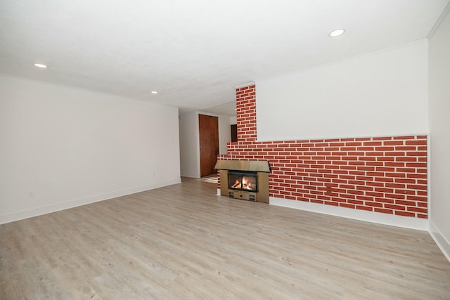 unfurnished living room with crown molding, baseboards, recessed lighting, wood finished floors, and a glass covered fireplace