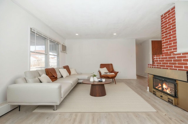 living area with recessed lighting, baseboards, a large fireplace, and wood finished floors