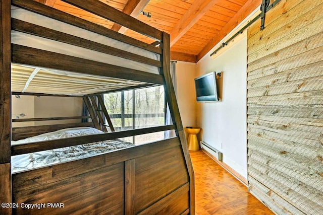 unfurnished bedroom with a barn door, a baseboard heating unit, wood finished floors, wood ceiling, and beamed ceiling