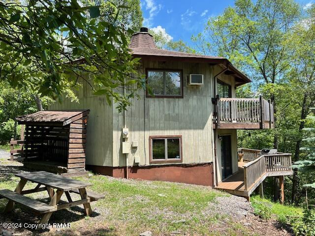 back of house with a chimney and a wooden deck