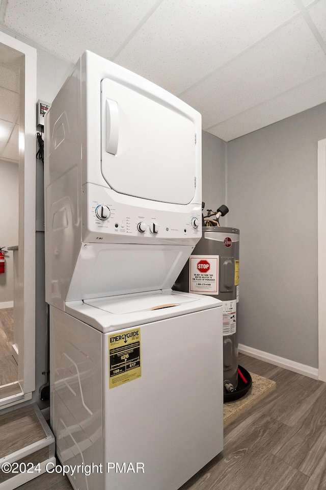 laundry area with laundry area, baseboards, stacked washer and clothes dryer, wood finished floors, and water heater