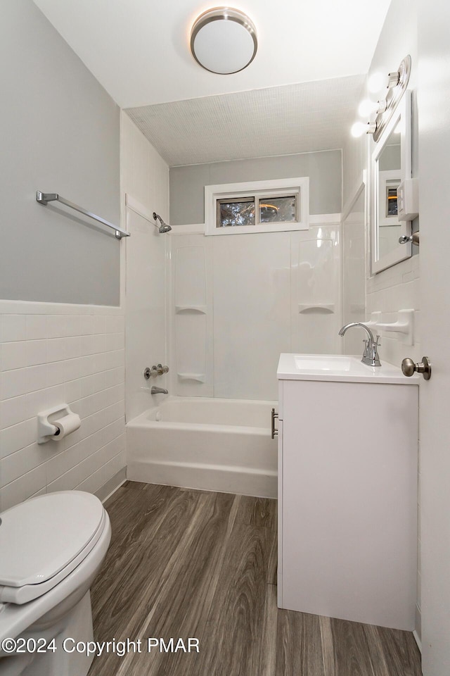 bathroom with tile walls, bathtub / shower combination, toilet, vanity, and wood finished floors