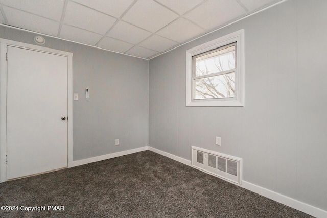 unfurnished room with dark colored carpet, baseboards, visible vents, and a drop ceiling