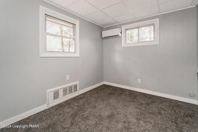 spare room with plenty of natural light, an AC wall unit, visible vents, and dark carpet