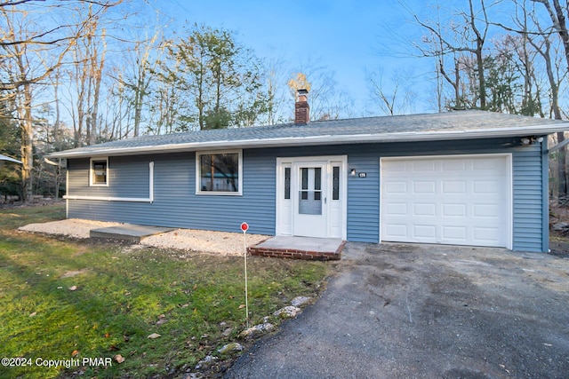 ranch-style home with a garage, a chimney, aphalt driveway, and roof with shingles