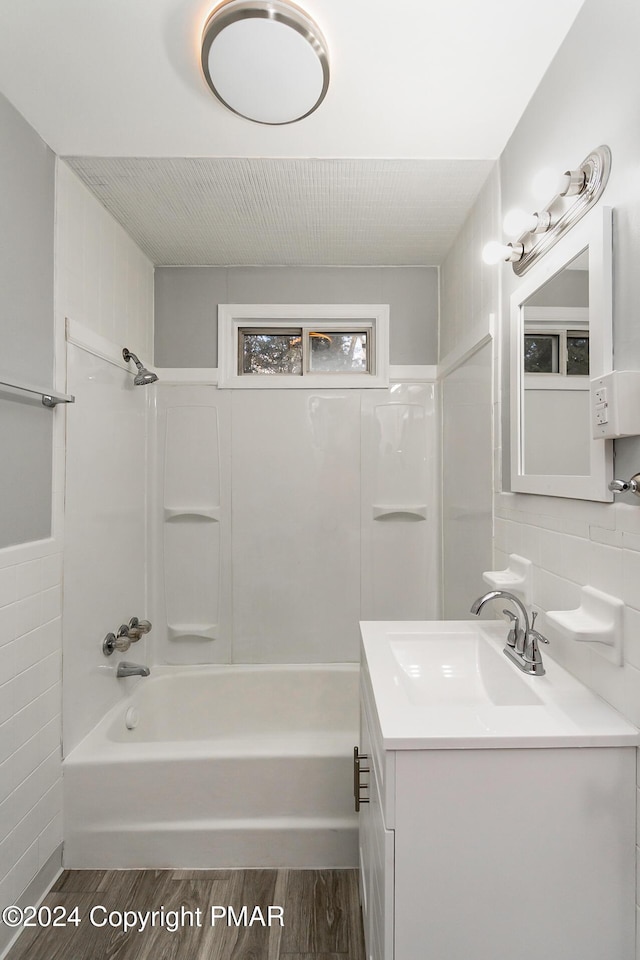 full bath with bathtub / shower combination, tile walls, vanity, and wood finished floors