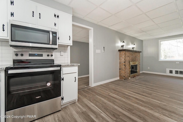 kitchen with visible vents, appliances with stainless steel finishes, wood finished floors, a fireplace, and backsplash