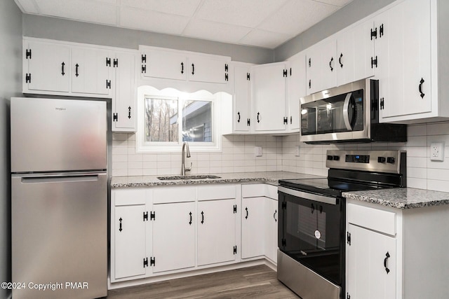 kitchen with decorative backsplash, dark wood-type flooring, stainless steel appliances, white cabinetry, and a sink