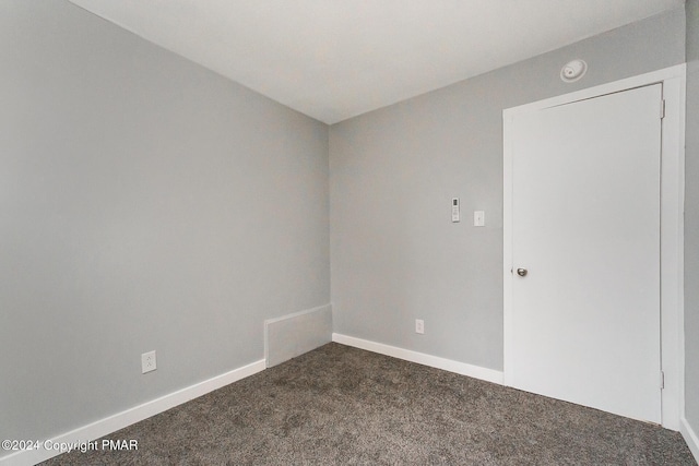 empty room with baseboards and dark colored carpet