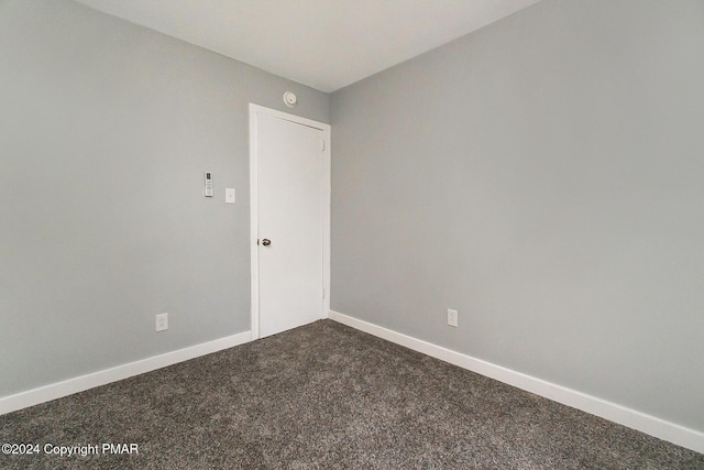 empty room with dark carpet and baseboards