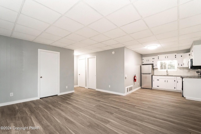 kitchen with visible vents, freestanding refrigerator, white cabinetry, a sink, and wood finished floors