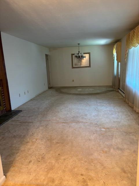 unfurnished living room with a baseboard heating unit and an inviting chandelier