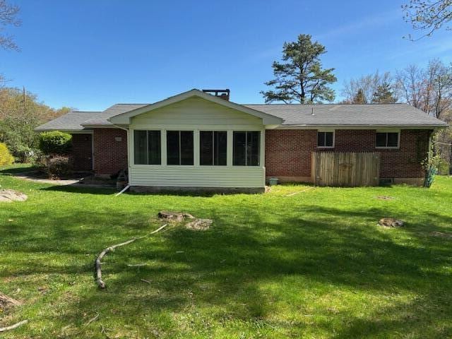 rear view of property with brick siding and a yard