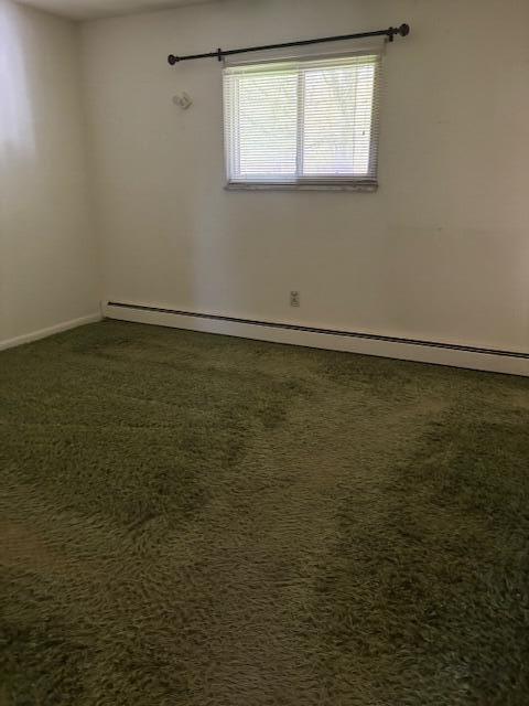 unfurnished room with baseboards, baseboard heating, and dark colored carpet