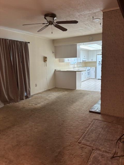 unfurnished living room with light colored carpet and a ceiling fan