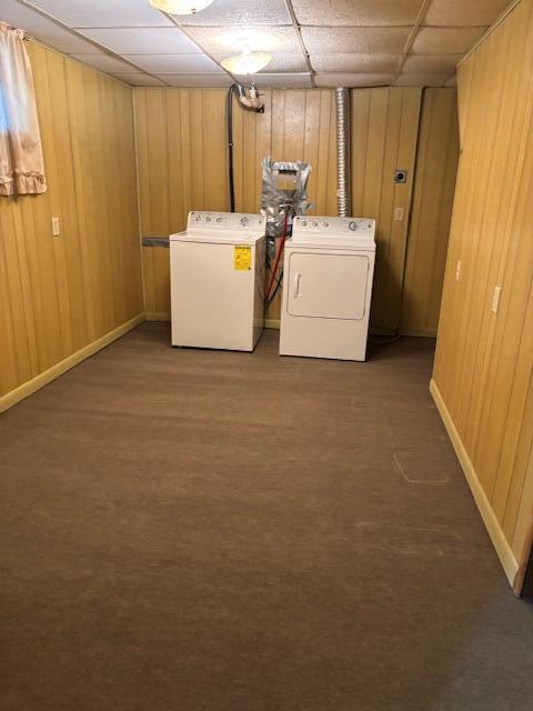 clothes washing area featuring carpet flooring, separate washer and dryer, laundry area, and wooden walls