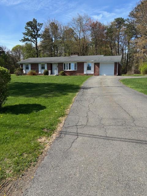 ranch-style home featuring brick siding, an attached garage, driveway, and a front yard
