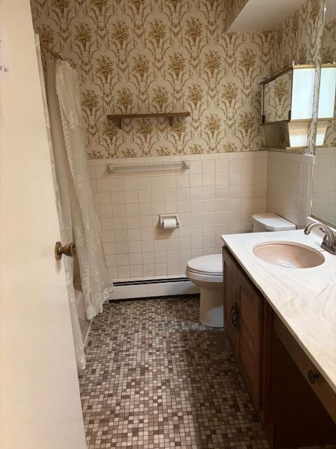 bathroom with wainscoting, vanity, toilet, wallpapered walls, and a baseboard radiator