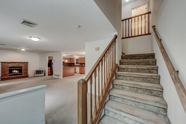 1162 Colt Ln, Pocono Summit, PA 18346 - stairway featuring carpet floors, a brick fireplace, and a ceiling fan
