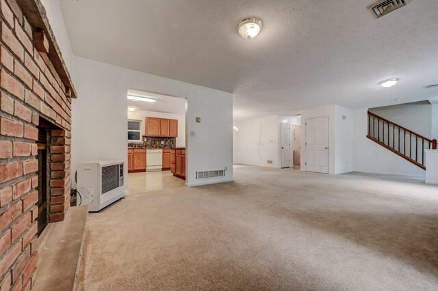 1162 Colt Ln, Pocono Summit, PA 18346 - unfurnished living room featuring light colored carpet, heating unit, a fireplace, and stairs